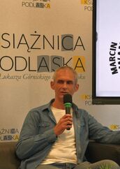 Marcin Silwanow siedzi na kanapie w Galerii Parter.